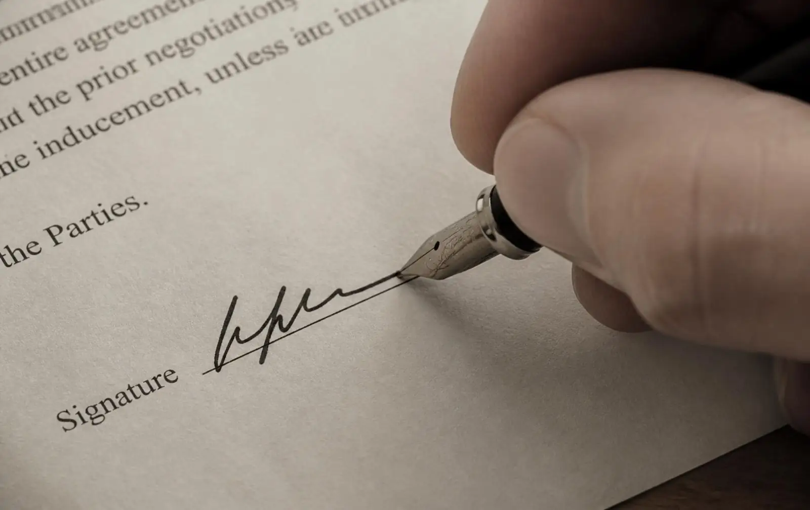 A hand signing a document with a fountain pen